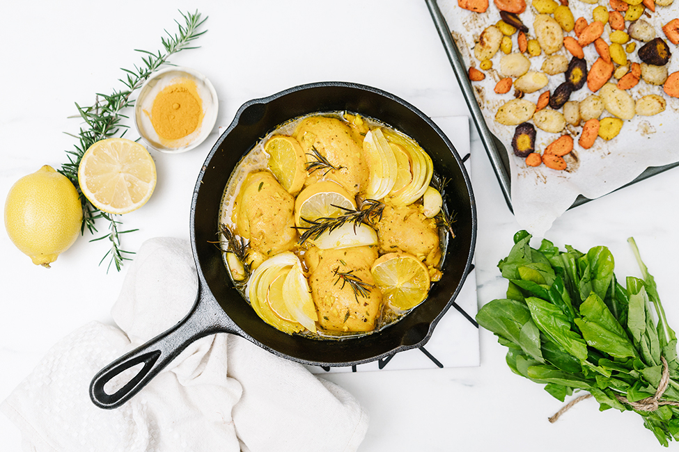 Baked lemon garlic chicken in a skillet on a white work surface