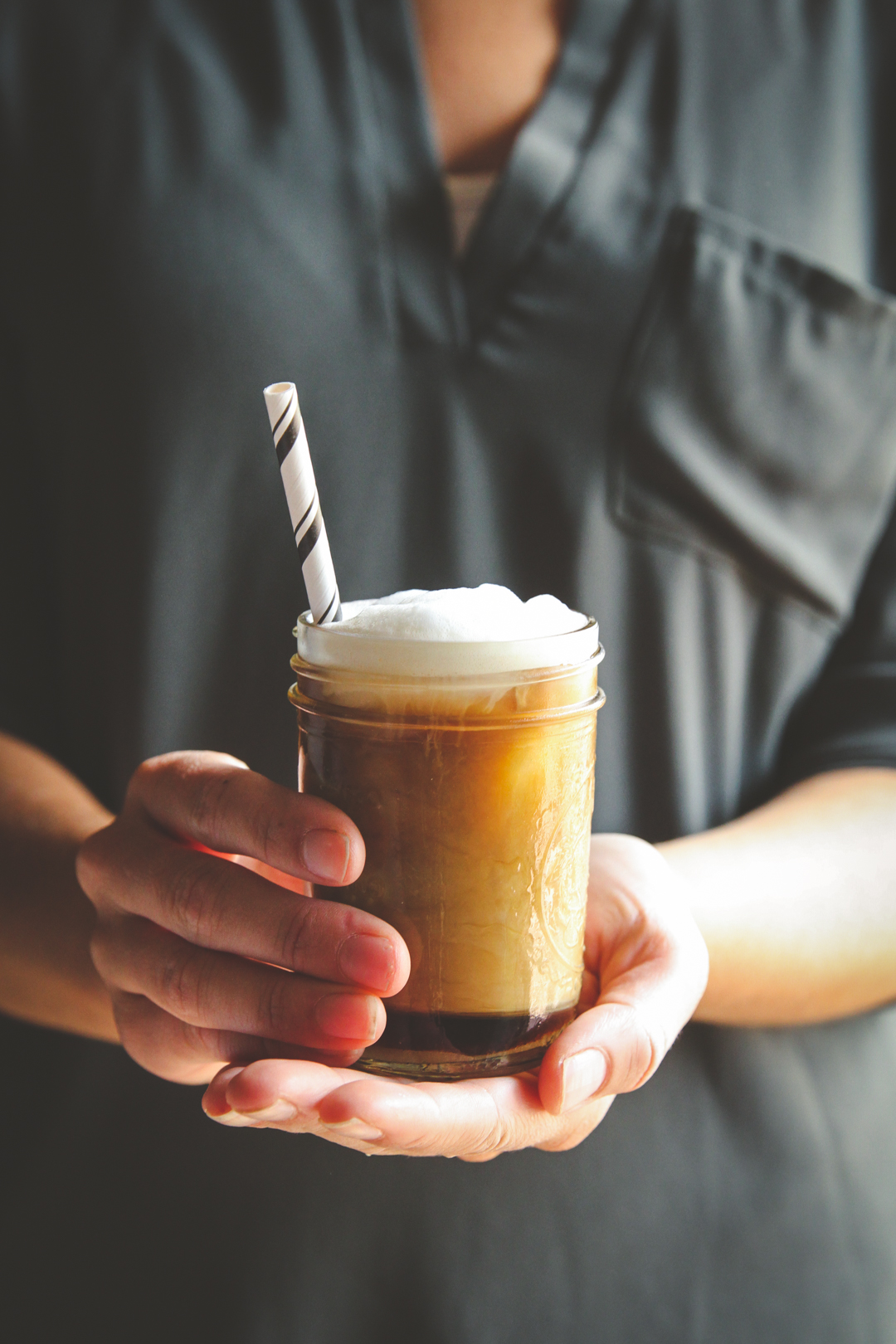 Coffee in a mason jar being held towards camera