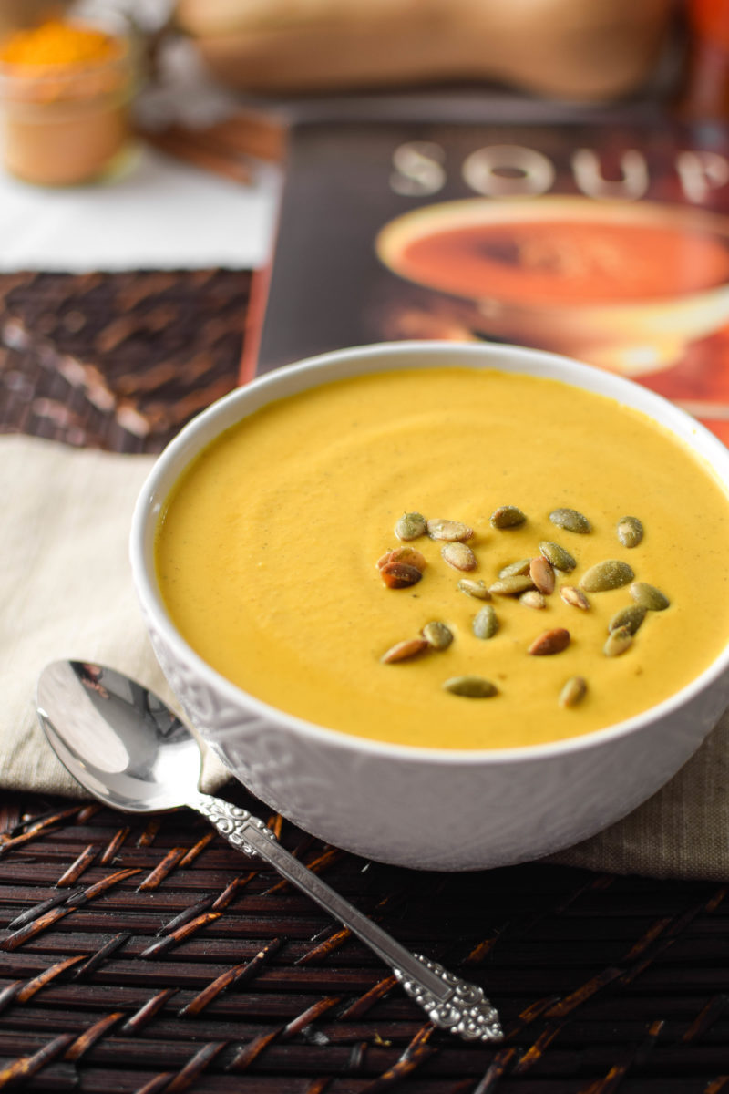 A yellow fall soup recipe served in a white bowl