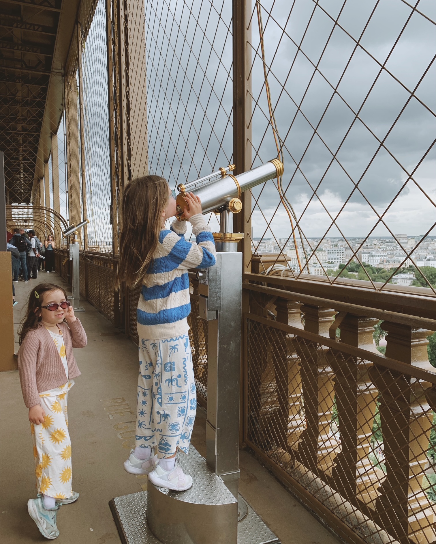 Kids looking out the telescope on the second floor of the eiffel tower in paris