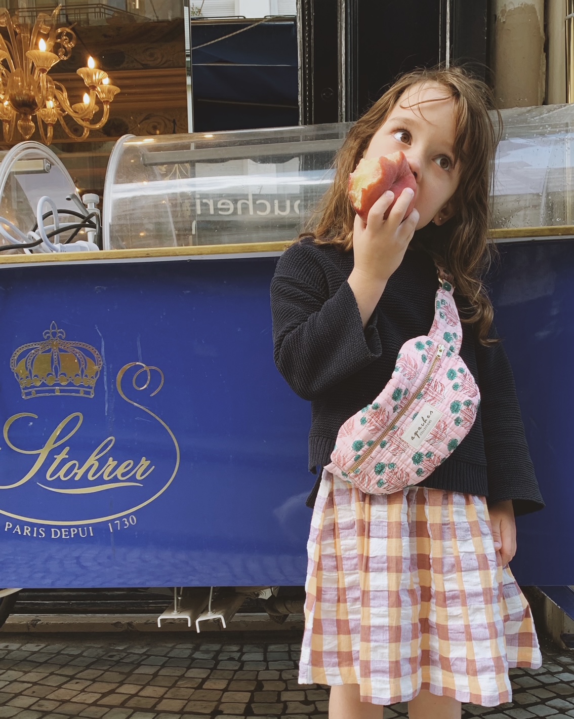 Child eating a peach on Rue Montorgueil in Paris