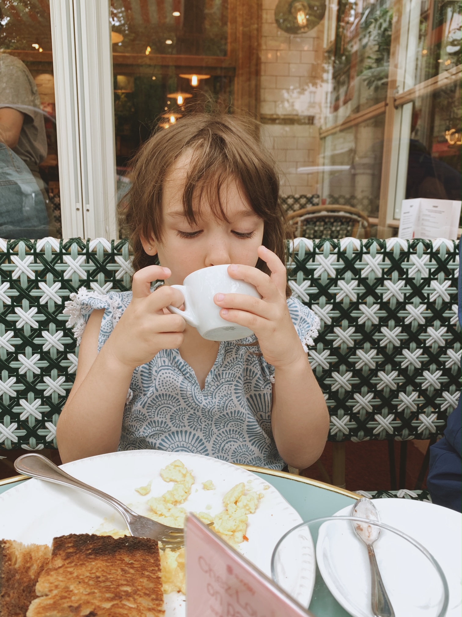 Child sipping a babyccino in a mug at Loulou's restaurant in paris