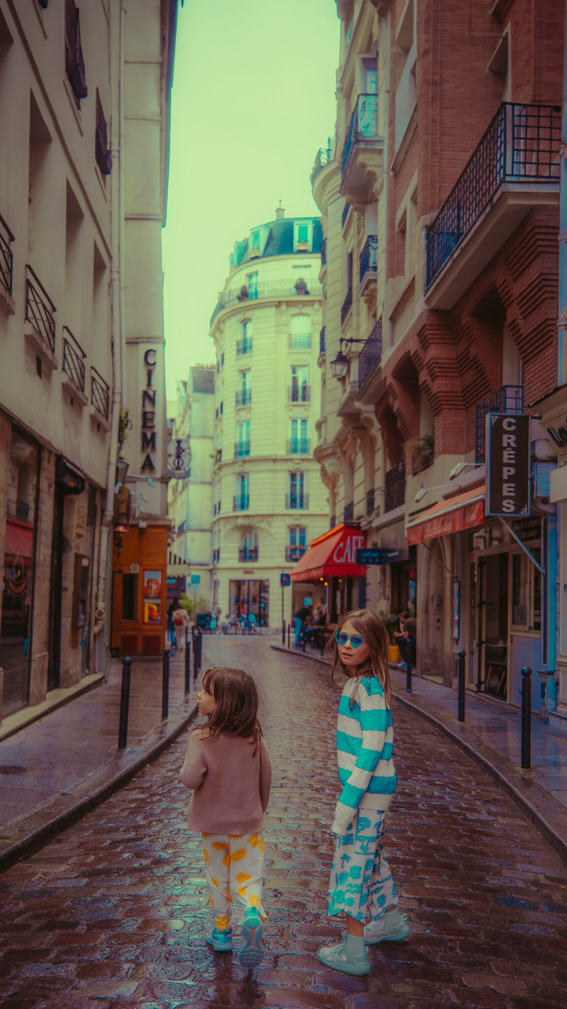 Two kids ages 5 and 9 in Paris, France in the summer. They are standing on a beautiful cobblestone street Saint Germain, Paris